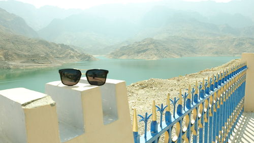 Sunglasses on built structure against lake