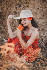 Full length of a smiling young woman holding hat