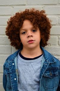 Portrait of boy standing against wall