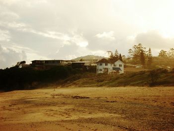 Houses on field against cloudy sky