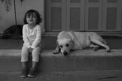 Portrait of cute girl with dog sitting against house