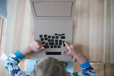 High angle view of boy playing with computer keys on table