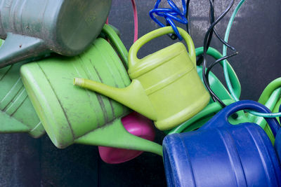 Close-up of plastic watering cans hanging against wall