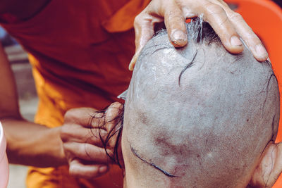 Midsection of monk cutting males hair