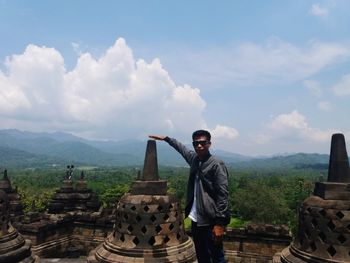 Full length of man standing on mountain against cloudy sky