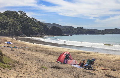 People relaxing on beach against sky