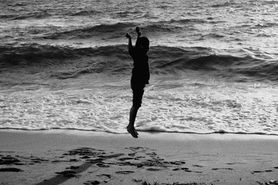 Boy jumping mid-air on shore at beach