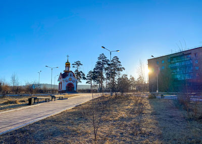Street amidst buildings against clear blue sky