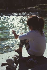 Rear view of girl sitting in water