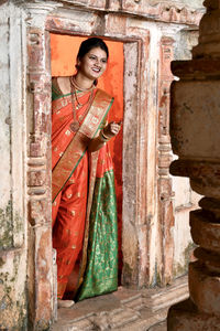 Portrait of young woman standing against wall