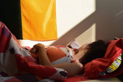 Side view of woman sleeping on bed at home