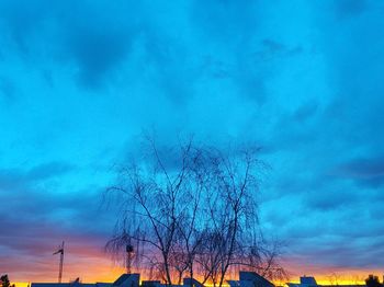 Low angle view of bare trees against cloudy sky