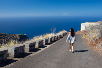 Rear view of woman walking on road