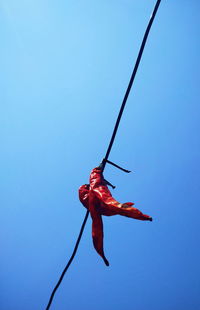 Low angle view of red rope against clear blue sky