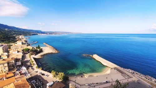 High angle view of townscape by sea against blue sky