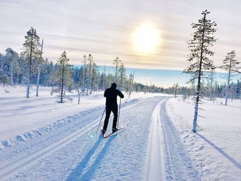 Rear view of man skiing on snowy field