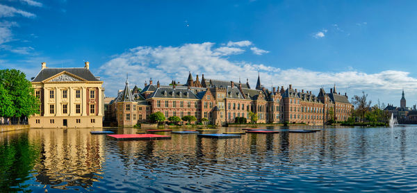 Buildings at waterfront against cloudy sky