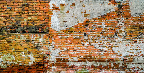 Old vintage red brick wall with fallen plaster