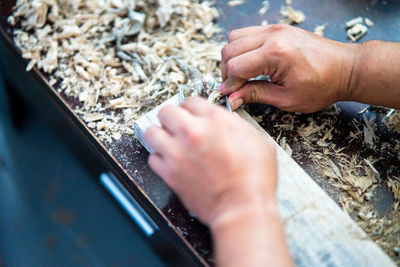 Midsection of person working on wooden plank.