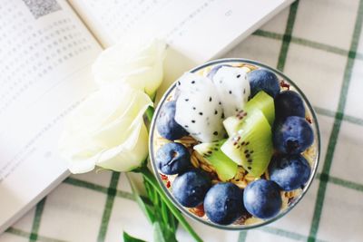 Directly above shot of fruit bowl by book on table