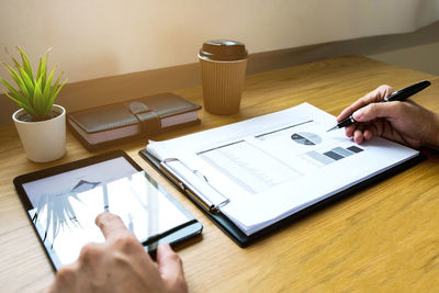 Cropped hand of businessman writing in graph on table