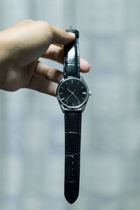 Close-up of hand holding black wristwatch