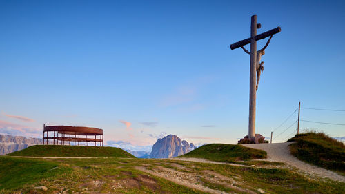 Cross on land against clear blue sky