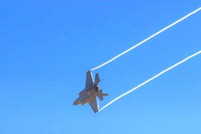 Low angle view of airplane flying against clear blue sky