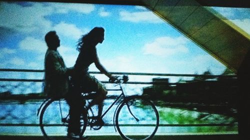 Reflection of man riding bicycle in puddle