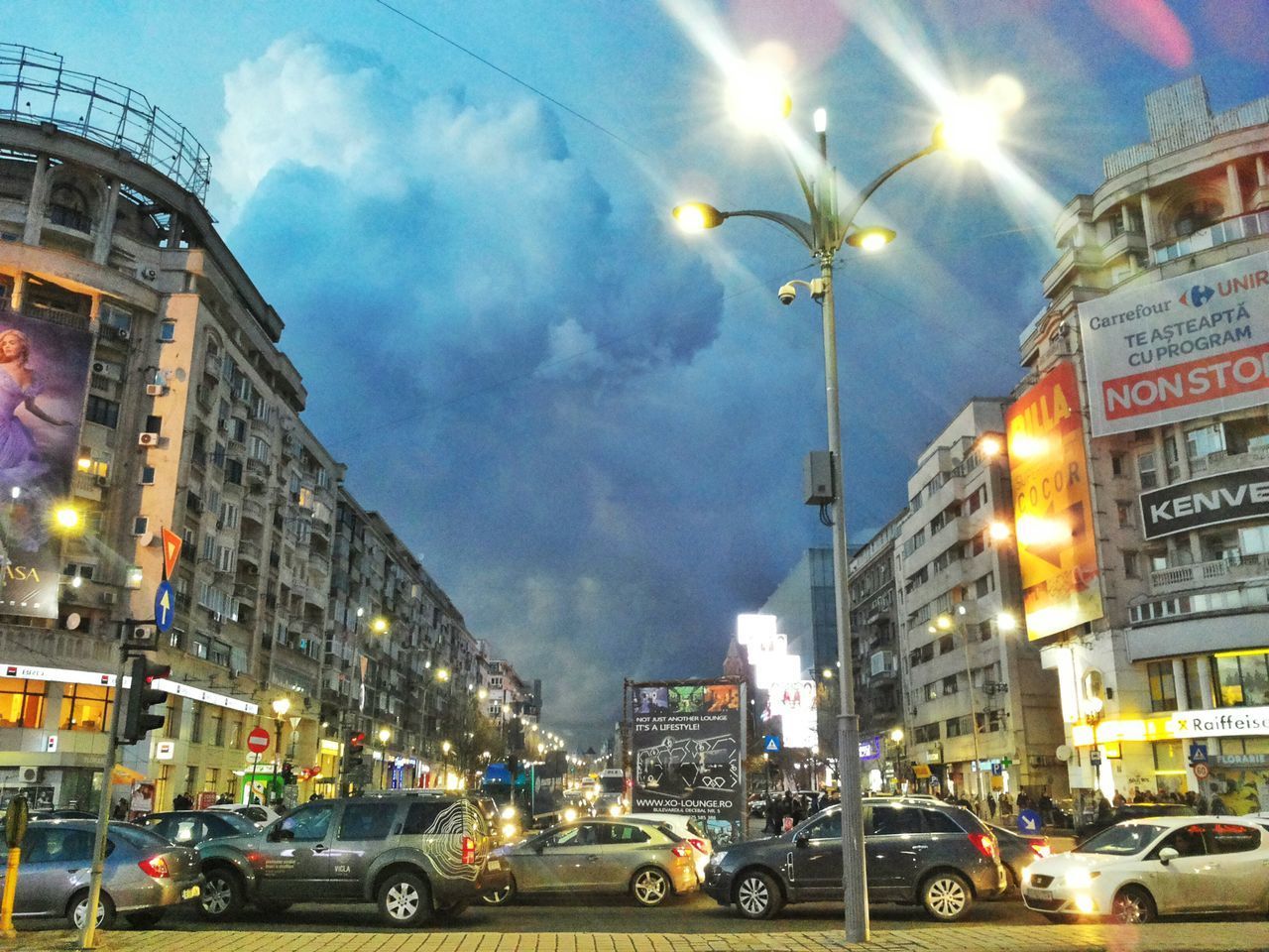 CARS ON ILLUMINATED CITY STREET AGAINST SKY