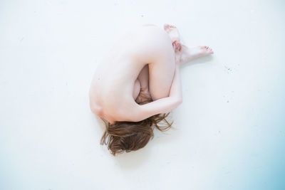 Directly above shot of naked woman lying on white background