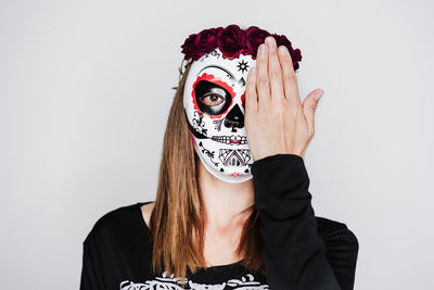 Portrait of young woman wearing mask against white background