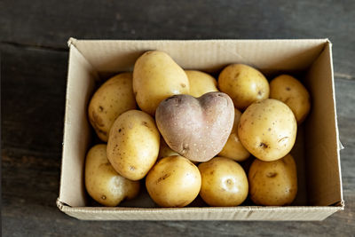 Red potato in the shape of a heart in a cardboard box among white potatoes