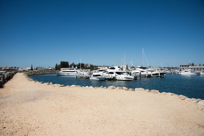 Boats moored at beach against blue sky