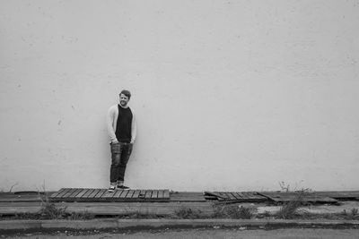 Young man looking down while standing against wall