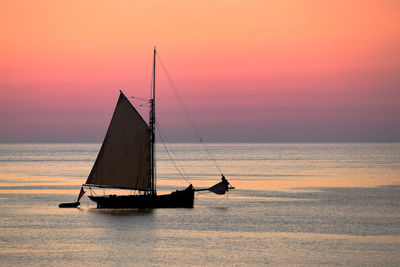 Sailboat sailing on sea against sky during sunset