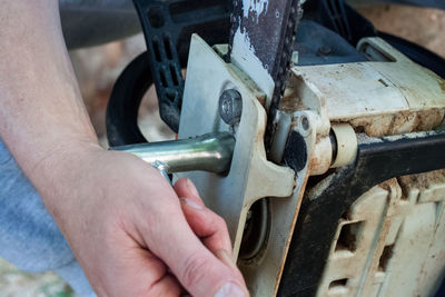 Midsection of man working repairing chainsaw