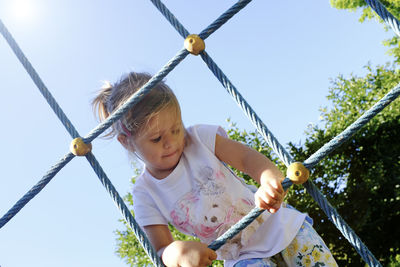 Low angle view of cute girl on jungle gym against sky