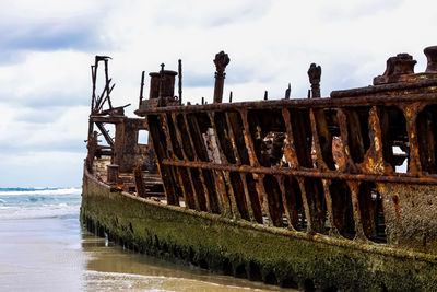 Abandoned boat on sea shore against sky