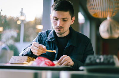 A young man eats fast food at a diner.