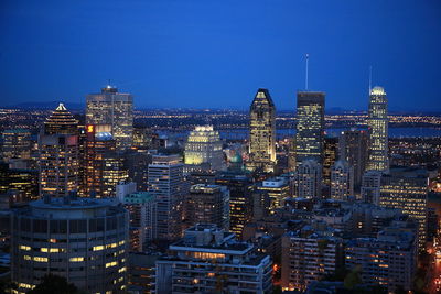 Illuminated cityscape against clear blue sky at night