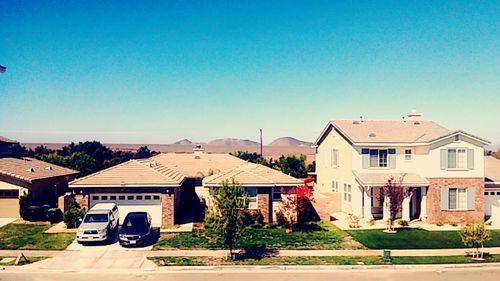 Houses in town against clear blue sky