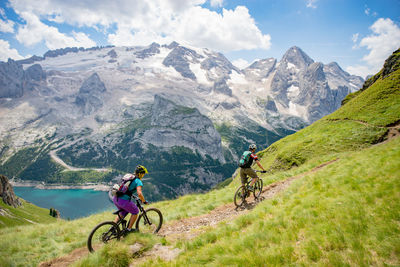 Man and woman riding their mountain bikes on footpath in the scenic dolomites, italy