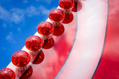 Low angle view of red lighting equipment against blue sky