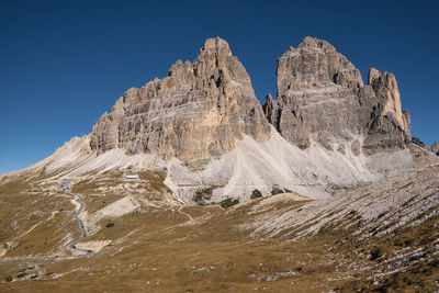 Low angle view of snowcapped mountains against clear blue sky