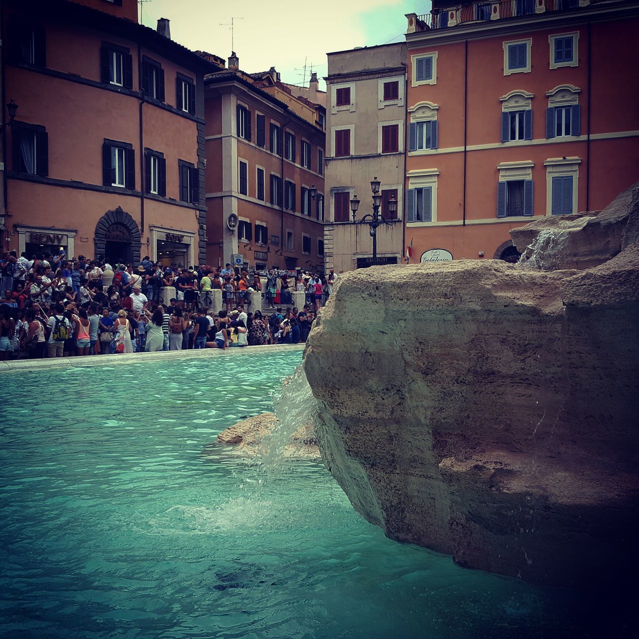 GROUP OF PEOPLE IN SWIMMING POOL AGAINST BUILDINGS