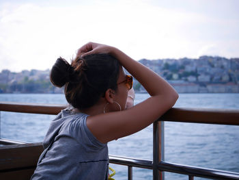 Full length of girl standing on railing against sea