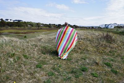 Person with towel on field against sky