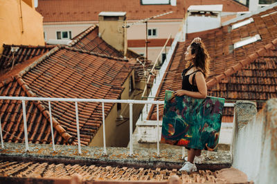 Woman standing holding abstract art painting while standing on roof