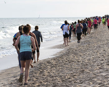 Rear view of people walking on beach